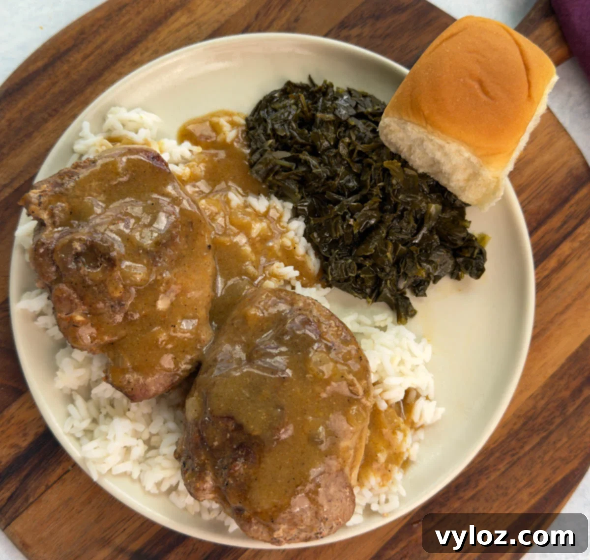 Overhead shot of a full plate—two turkey chops over rice with brown gravy, collard greens, and a roll on the side.