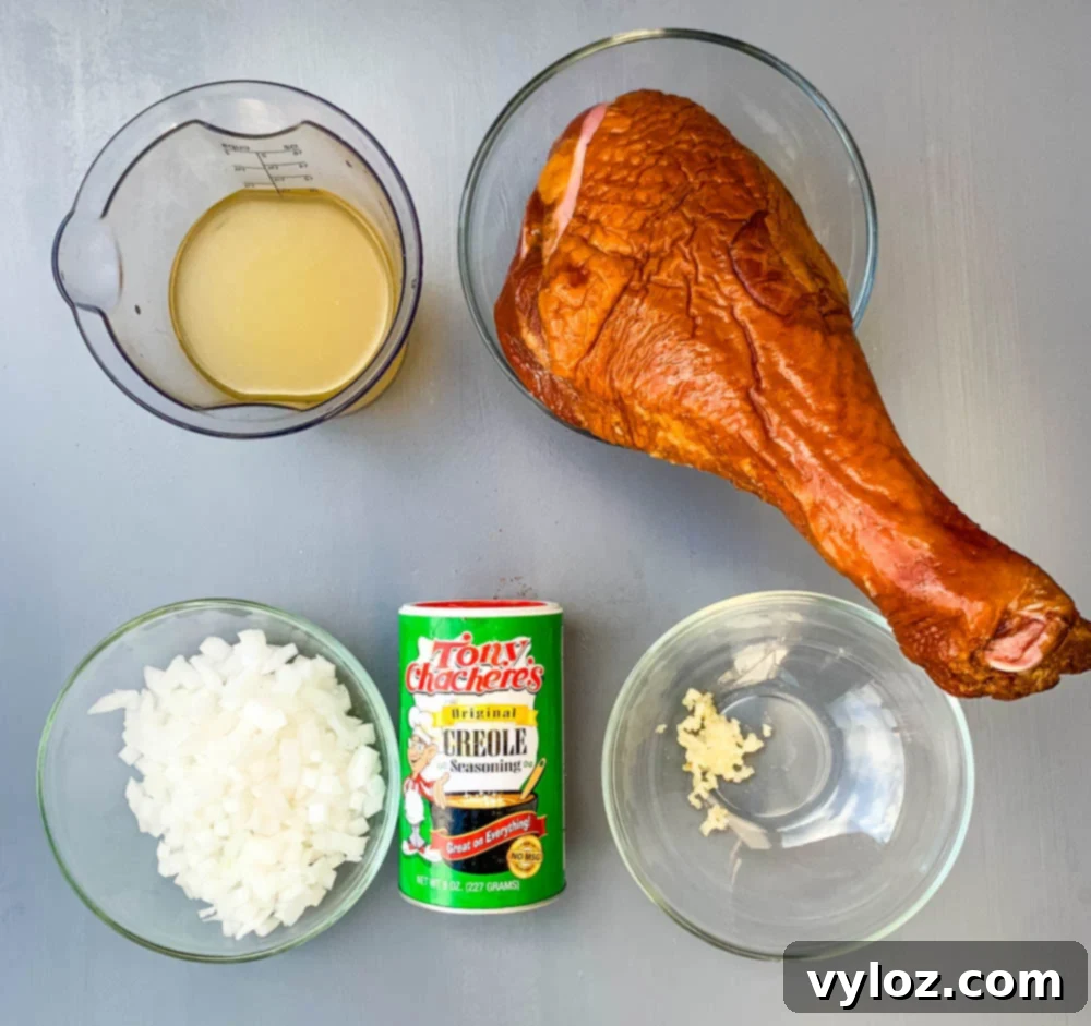 chicken broth, chopped onions and garlic, a smoked turkey leg, and Creole seasoning on a flat surface