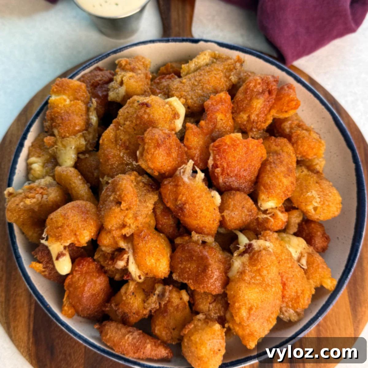 Overhead view of a large bowl filled with crispy fried cheese curds, showing crunchy coating and bits of melty cheese peeking through.