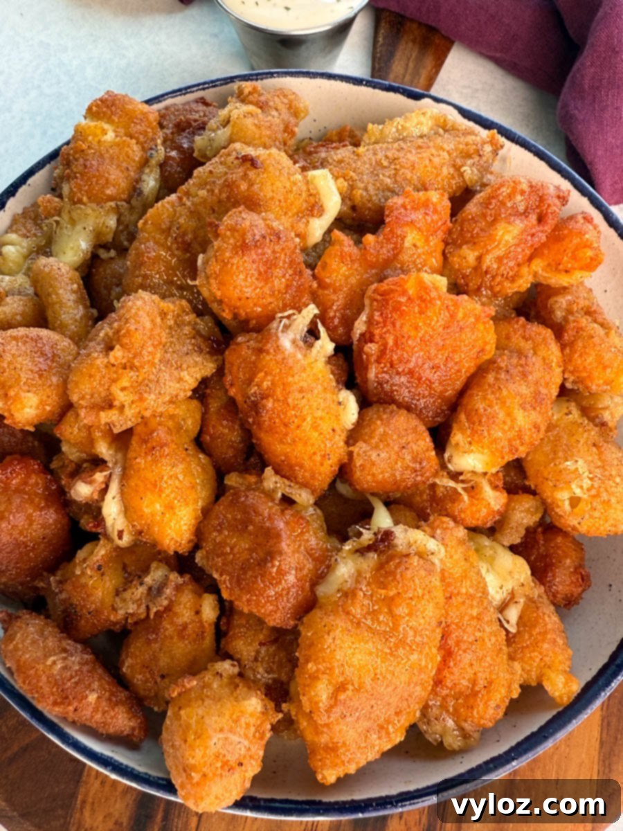 Angled close-up of crispy cheese curds in a bowl, highlighting their golden coating and melty cheese edges.