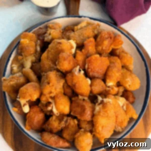 Overhead view of a large bowl filled with crispy fried cheese curds, showing crunchy coating and bits of melty cheese peeking through.