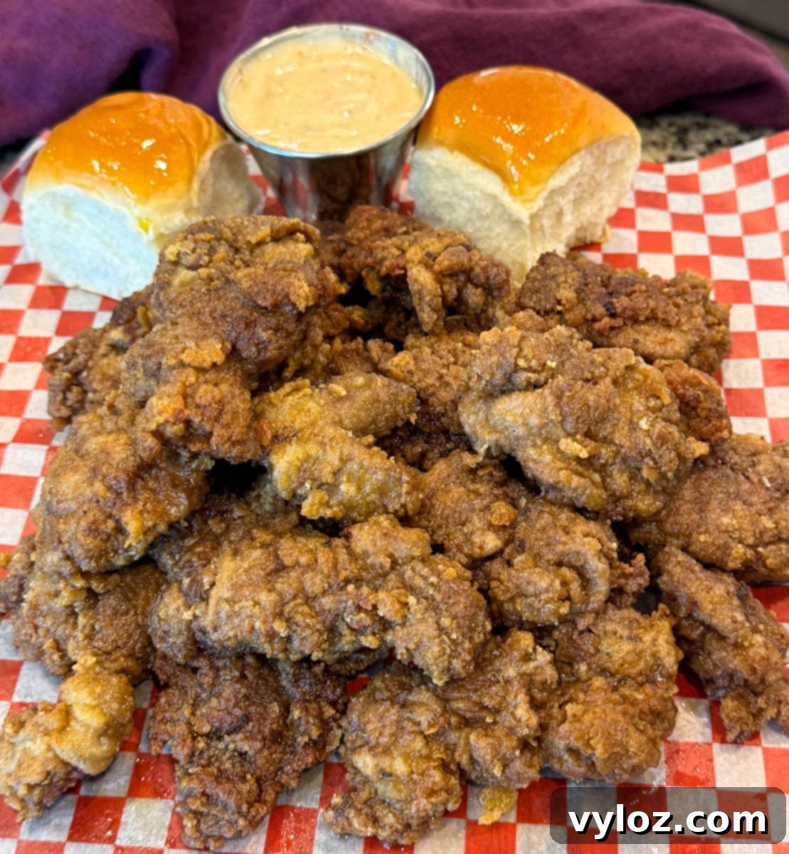 Crispy Fried Chicken Livers 13 Crispy fried chicken livers stacked on checkered paper, paired with dinner rolls and a dipping sauce.