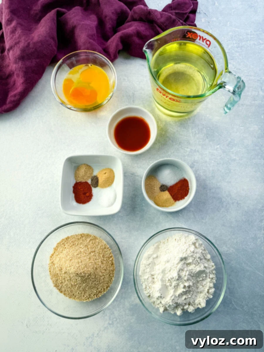 Crispy Fried Chicken Livers 5 Eggs, hot sauce, flour, breadcrumbs, seasonings, and oil measured out in bowls and a measuring cup, all arranged neatly on a light countertop.