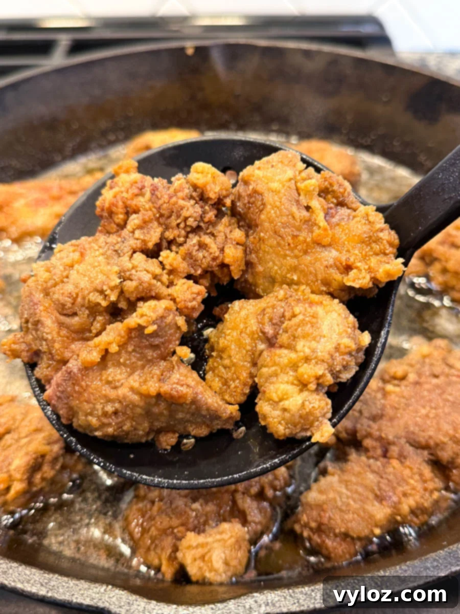 Crispy Fried Chicken Livers 8 Fried chicken livers being lifted from hot oil with a slotted spoon.