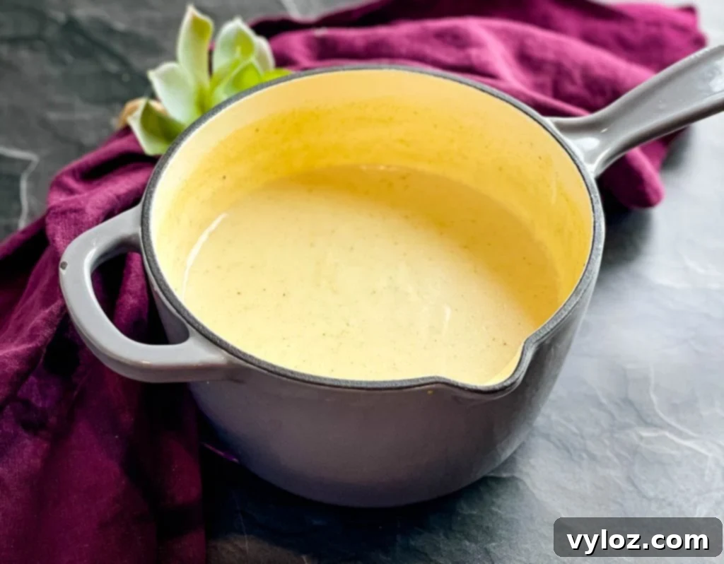 Homemade cream of chicken soup simmering in a saucepan on the stove, showing its smooth, thickened texture.