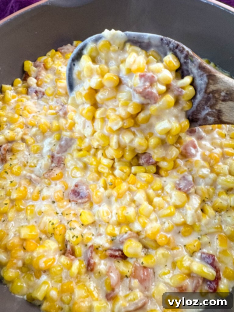 Southern Soul Food Creamed Corn in a skillet with a wooden spoon, showcasing its creamy texture.