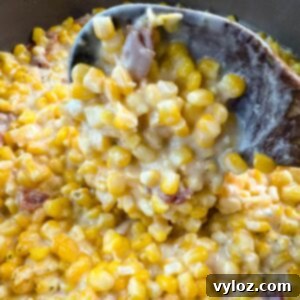 Southern creamed corn in a pot with a wooden spoon.