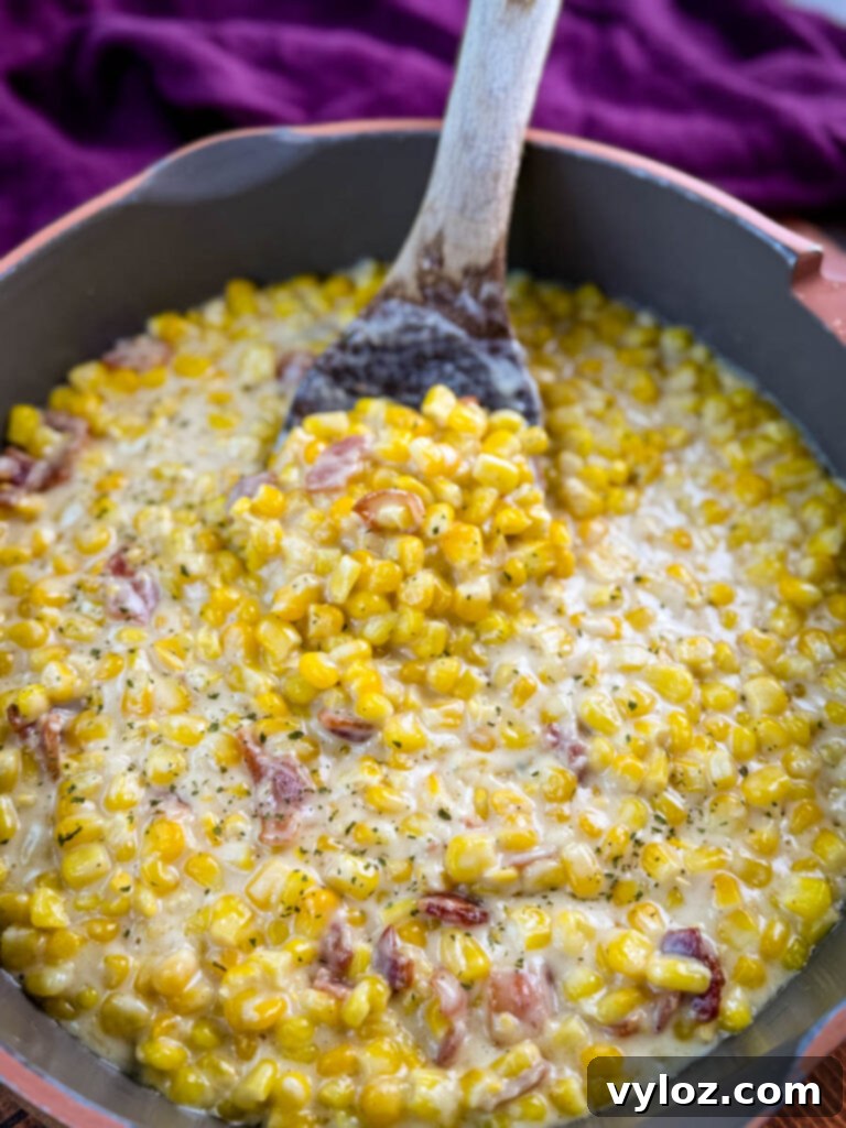Southern creamed corn being served from a skillet onto a spoon, highlighting its creamy texture.