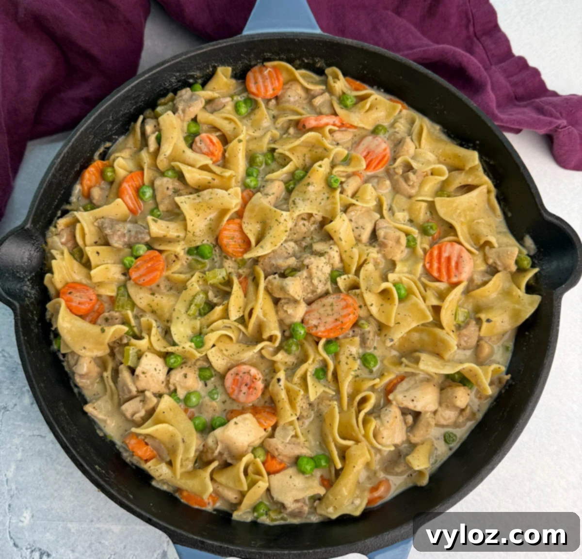 Overhead view of the finished one-pot chicken pot pie casserole with noodles, carrots, peas, and chicken, showing the creamy sauce texture and hearty mix of ingredients.