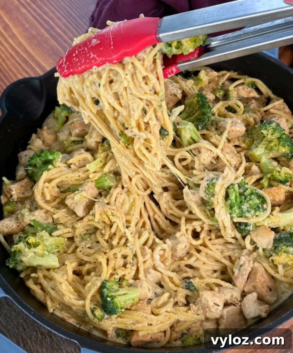 creamy chicken broccoli Alfredo with tongs in a skillet, showcasing a perfect one-pot meal