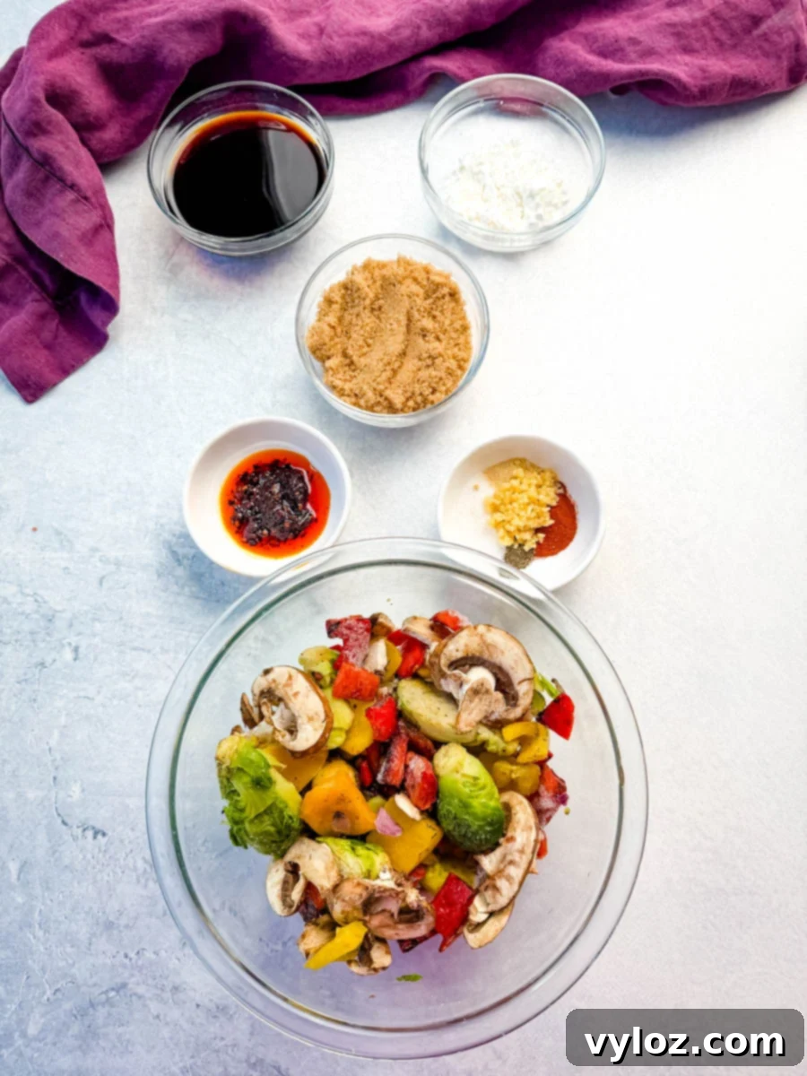 Overhead photo showing prepped ingredients for Mongolian ground beef with udon noodles, including a bowl of chopped mixed vegetables (Brussels sprouts, bell peppers, mushrooms), and small bowls of soy sauce, brown sugar, garlic, cornstarch, and seasonings arranged neatly on a light countertop with a purple cloth in the background, ready to be combined.