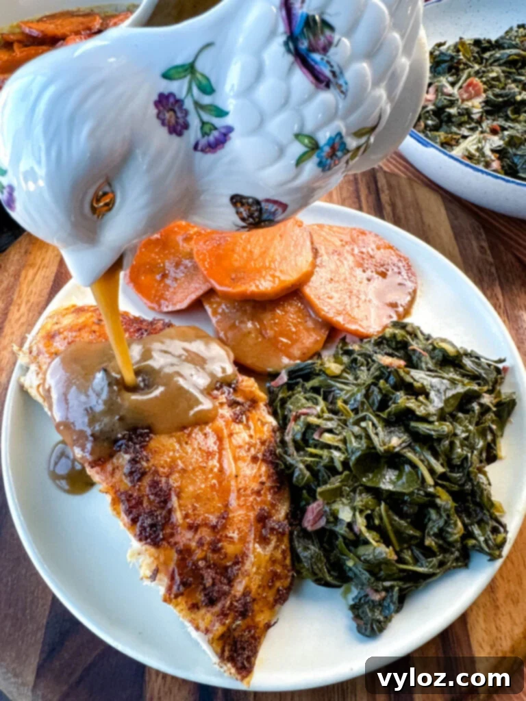 Spicy Cajun Turkey 10 gravy drizzled over Cajun turkey on a plate with gravy, collard greens, and candied sweet potatoes