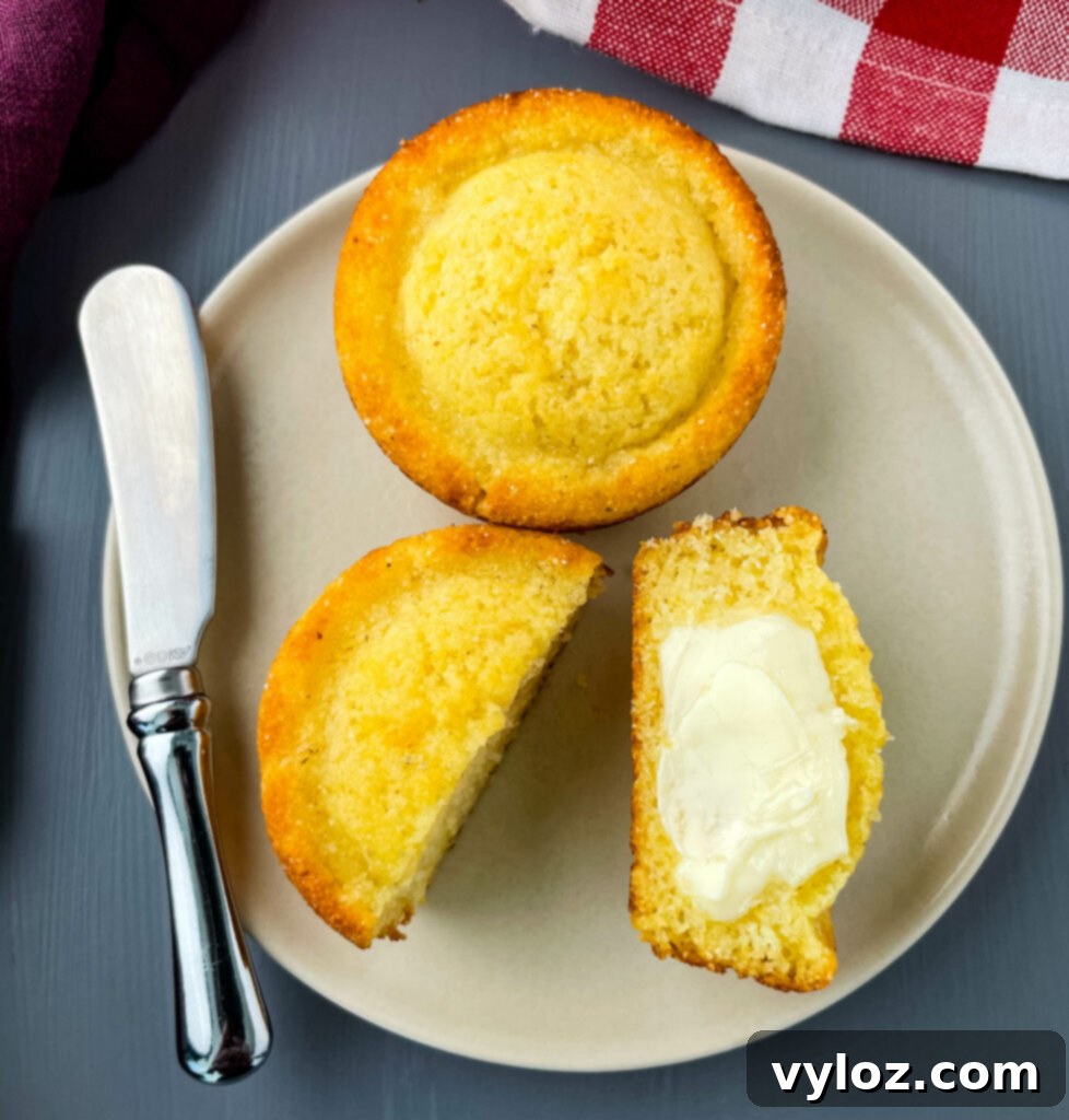A warm cornbread muffin, perfectly sliced in half, generously drizzled with melted butter, ready to be enjoyed.