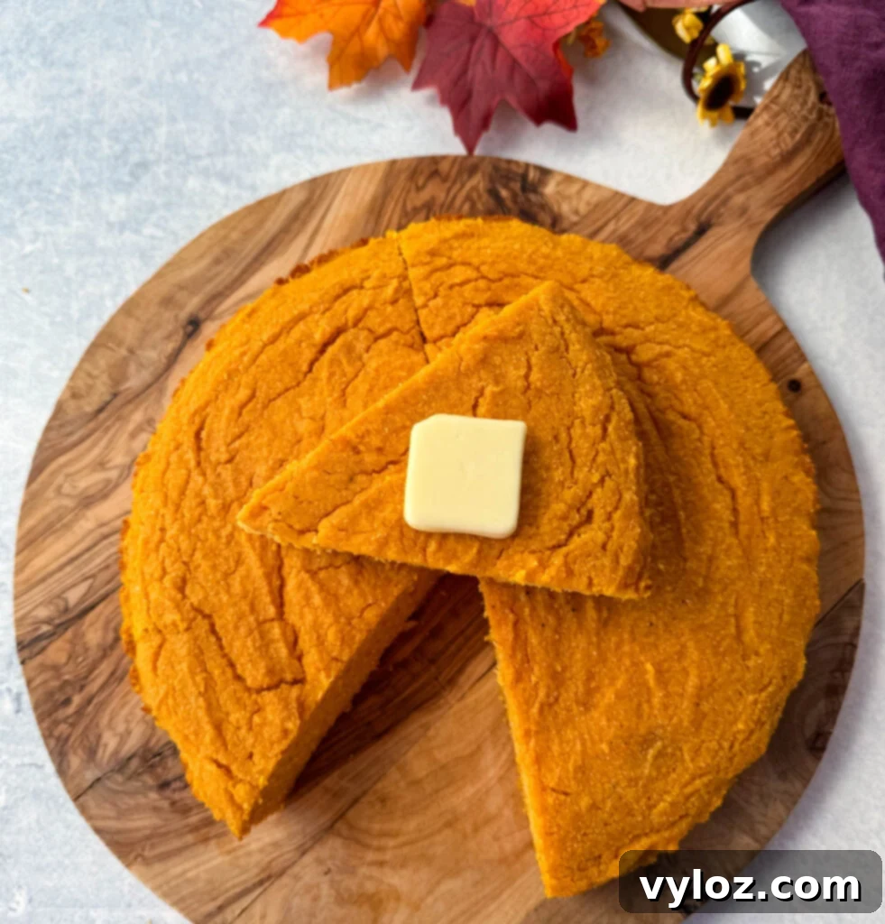 a slice of sweet potato cornbread with butter on top of a pan of sweet potato cornbread