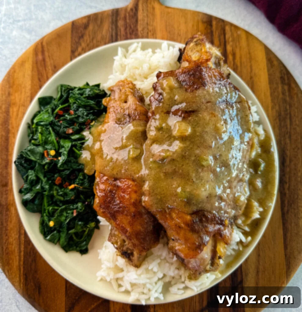 Soulful Smothered Turkey Wings 12 A generous serving of smothered turkey wings with white rice and cooked spinach on a white plate