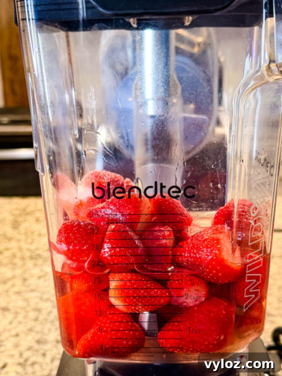 Hennessy Midnight Slush 4 Frozen strawberries being added to a blender for the Hennessy slushie.