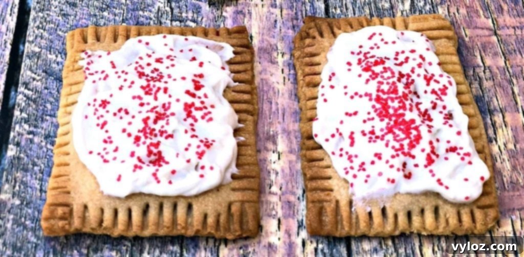Golden brown air fryer homemade strawberry pop tarts, freshly baked and ready to be frosted, arranged on a rustic wooden surface with a scattering of fresh strawberries.