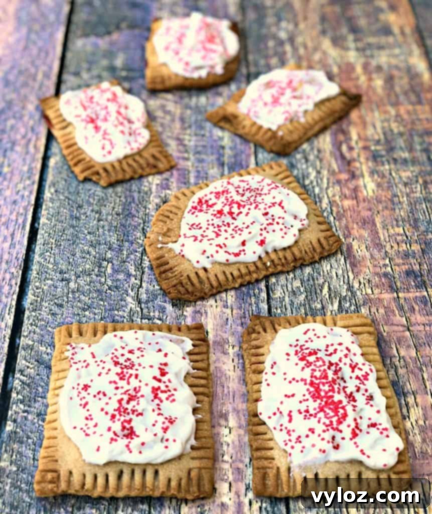 Two air fryer strawberry pop tarts, one bitten to reveal the sweet strawberry filling, resting on a vibrant, multi-colored serving tray.