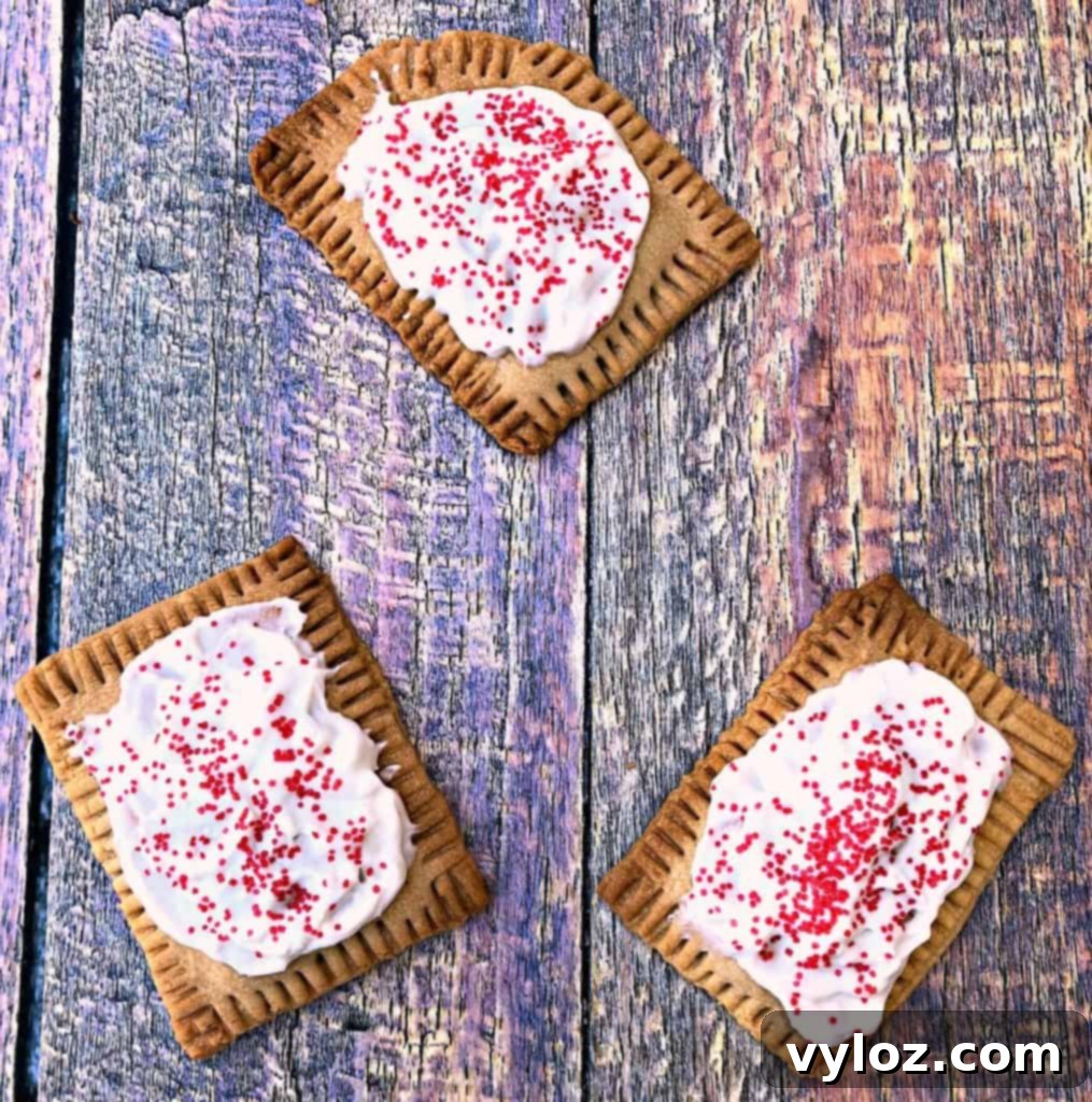 Four golden-brown air fryer strawberry pop tarts, warm and unfrosted, displayed on a colorful, patterned serving surface.