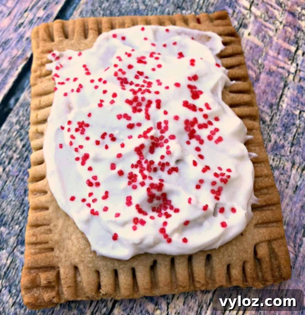 A close-up of air fryer strawberry pop tarts, perfectly golden and unfrosted, showcasing their flaky crust, arranged on a vibrant, multi-colored serving plate.