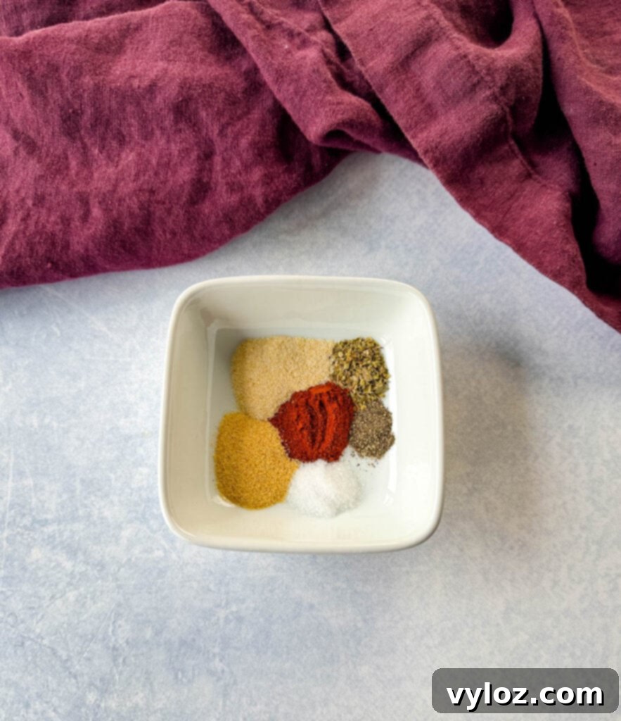 homemade spice blend with smoked paprika, garlic powder, onion powder, oregano, salt, and pepper in a white bowl