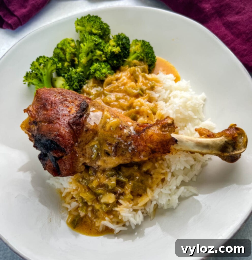 baked turkey leg on a plate with rice, gravy, and broccoli