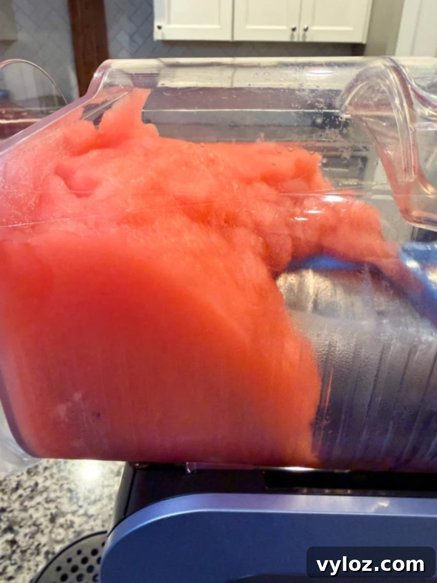 Frozen slushi mixture inside the Ninja Slushi machine showing a smooth, fluffy red texture.