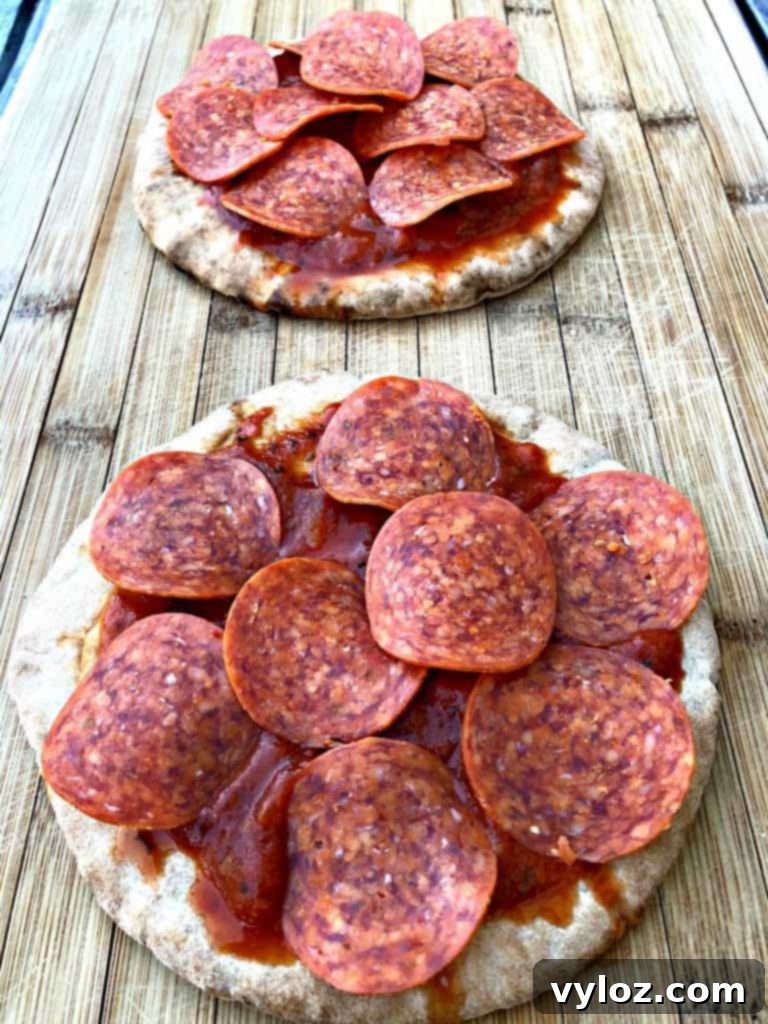 Pita bread crust spread with marinara pizza sauce and topped with savory pepperoni slices