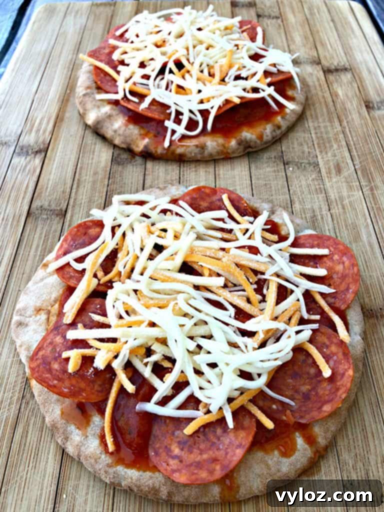 Pita bread base topped with marinara sauce, pepperoni, and a generous layer of mozzarella cheese, ready for the air fryer