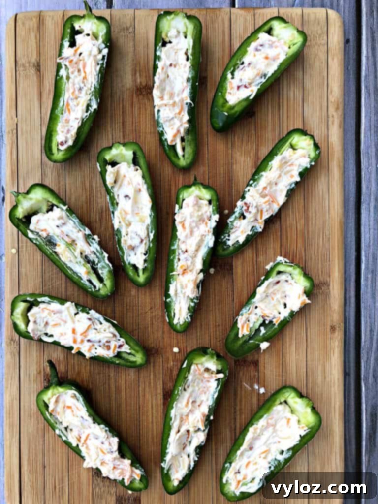 fresh jalapenos sliced in half on a cutting board stuffed with cheese