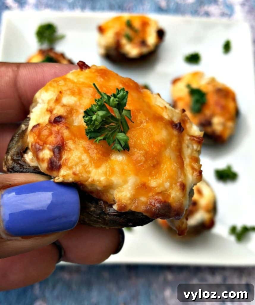 Golden Cheesy Air Fryer Mushrooms 7 Person holding a single cooked air fryer cheese stuffed mushroom, showing its size