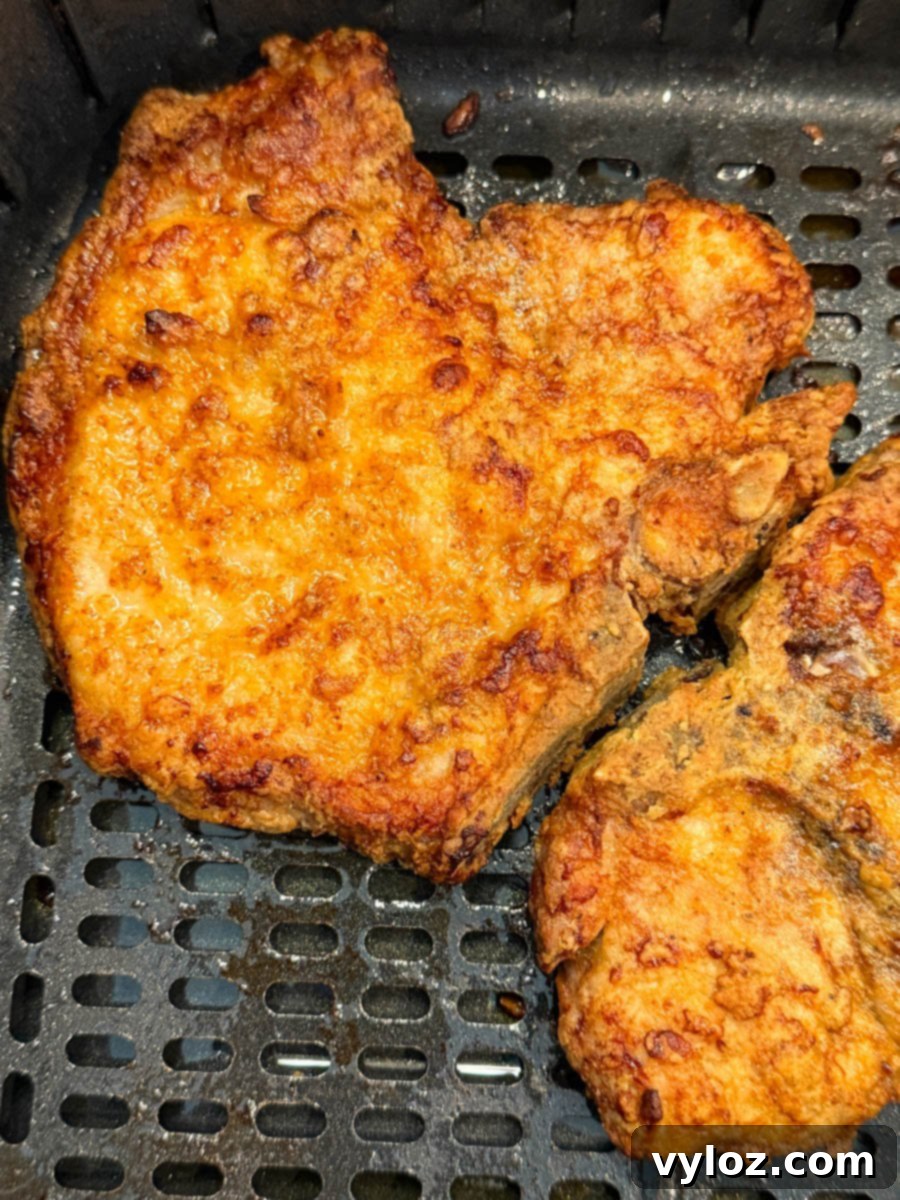 Close-up of crispy pork chops in the air fryer basket, showing their golden texture and color.