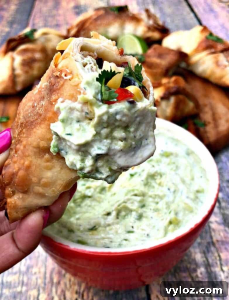 Another view of a halved air fryer southwestern egg roll next to avocado ranch dip, highlighting the texture and colors.