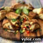 Air fryer southwestern egg rolls cut in half with black beans, corn, and red peppers spread out on a brown cutting board