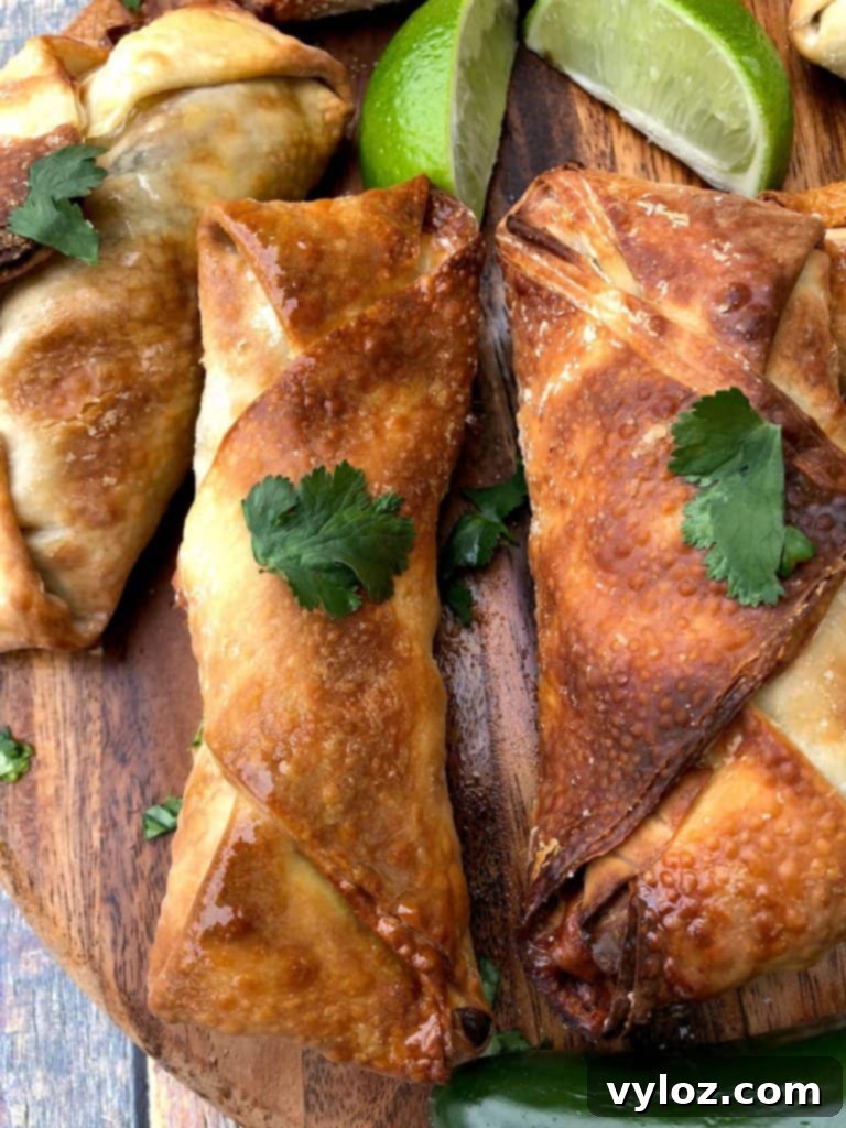 A selection of air fryer southwestern egg rolls laid out on a brown cutting board, showcasing their golden-brown crispness.