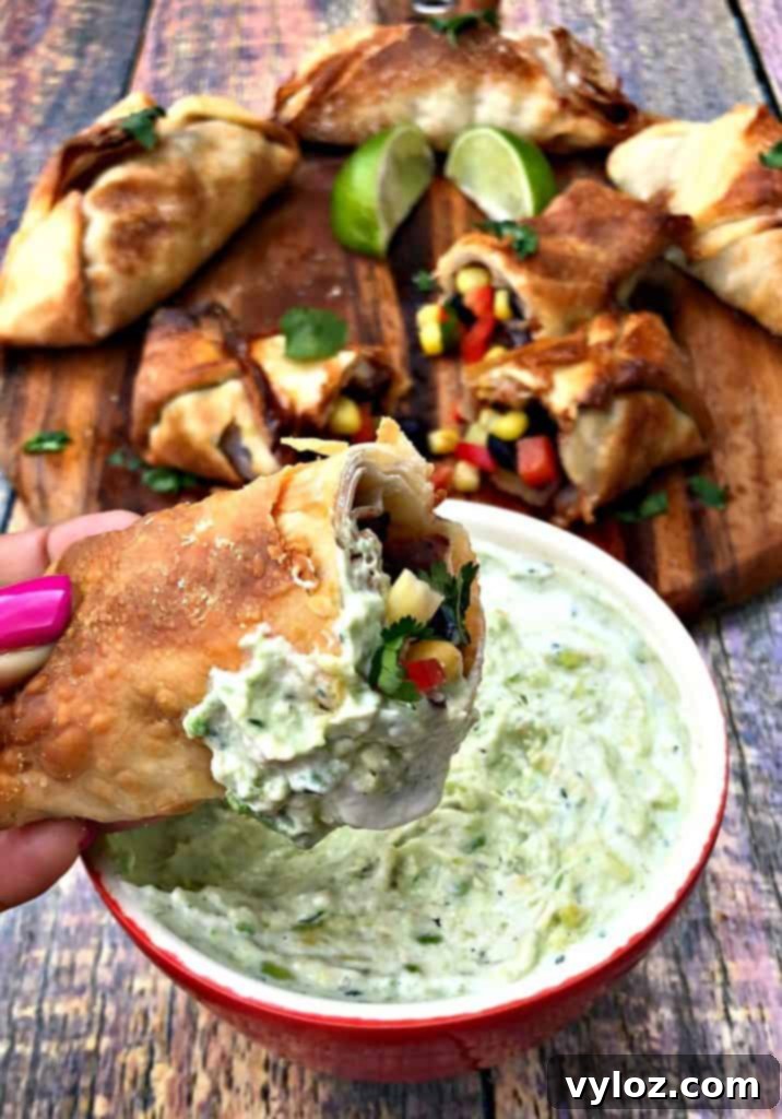 A crispy air fryer southwestern egg roll, sliced in half, poised next to a bowl of creamy avocado ranch dip, ready to be enjoyed.