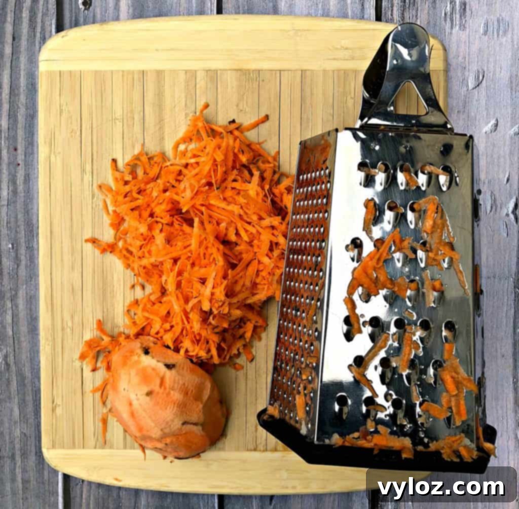 Raw sweet potato shredded next to a cheese grater, showing the texture before preparation