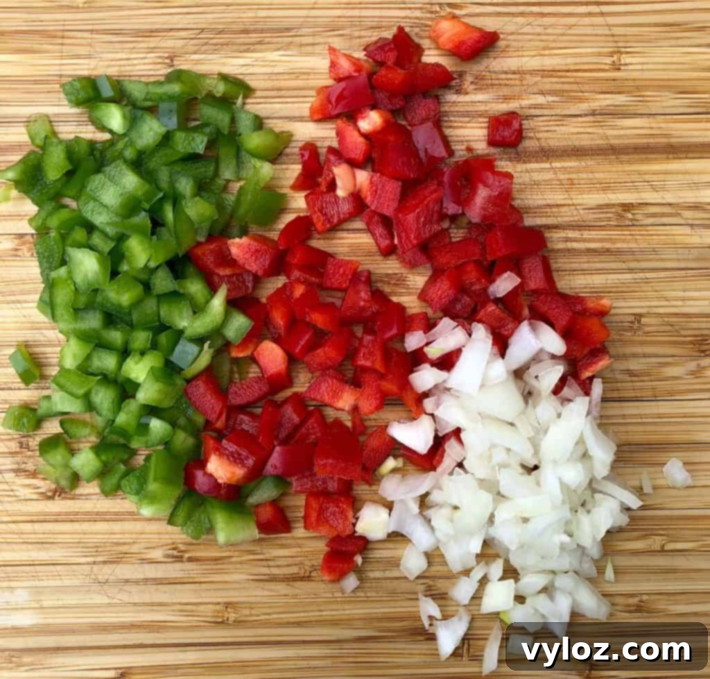 Perfectly Crispy Air Fryer Hash Browns 4 chopped red and green peppers and chopped onions on a cutting board, ready to be added to hash browns