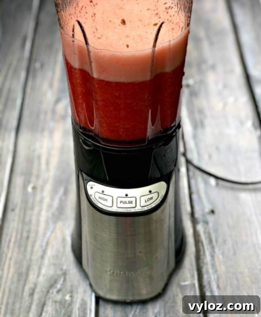 The Rosé wine and fruit mixture being poured into a blender, ready for the next step in making popsicles.