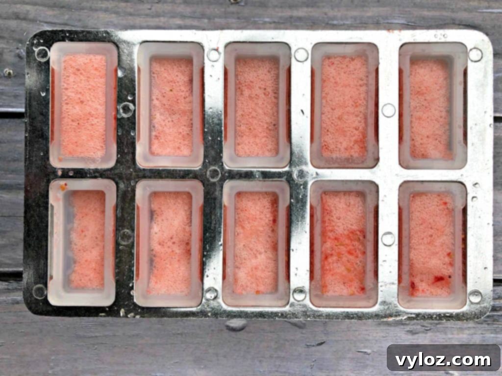 Close-up of Rosé wine popsicles in a mold, showing the fresh fruit visible within the liquid before freezing.