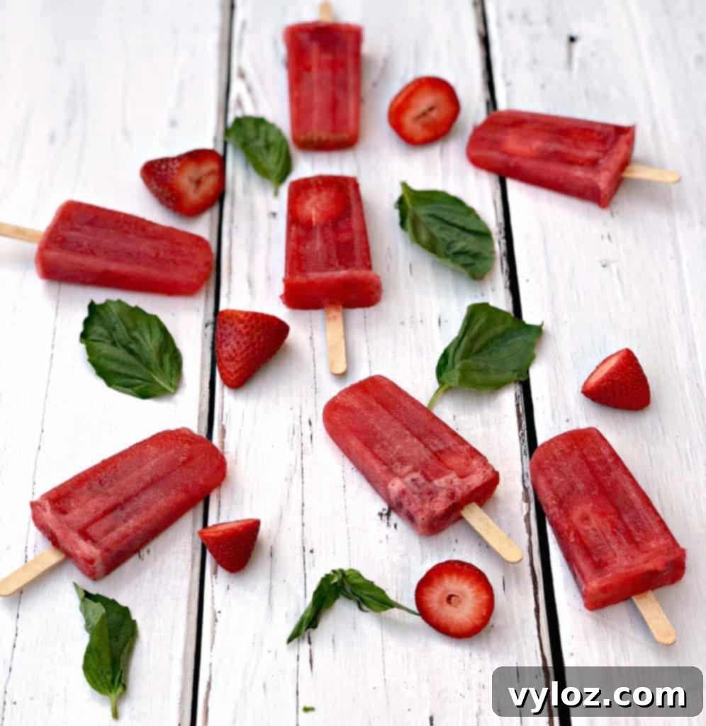 Close-up of a refreshing Rosé wine popsicle with strawberry and basil garnish, held ready to be enjoyed.