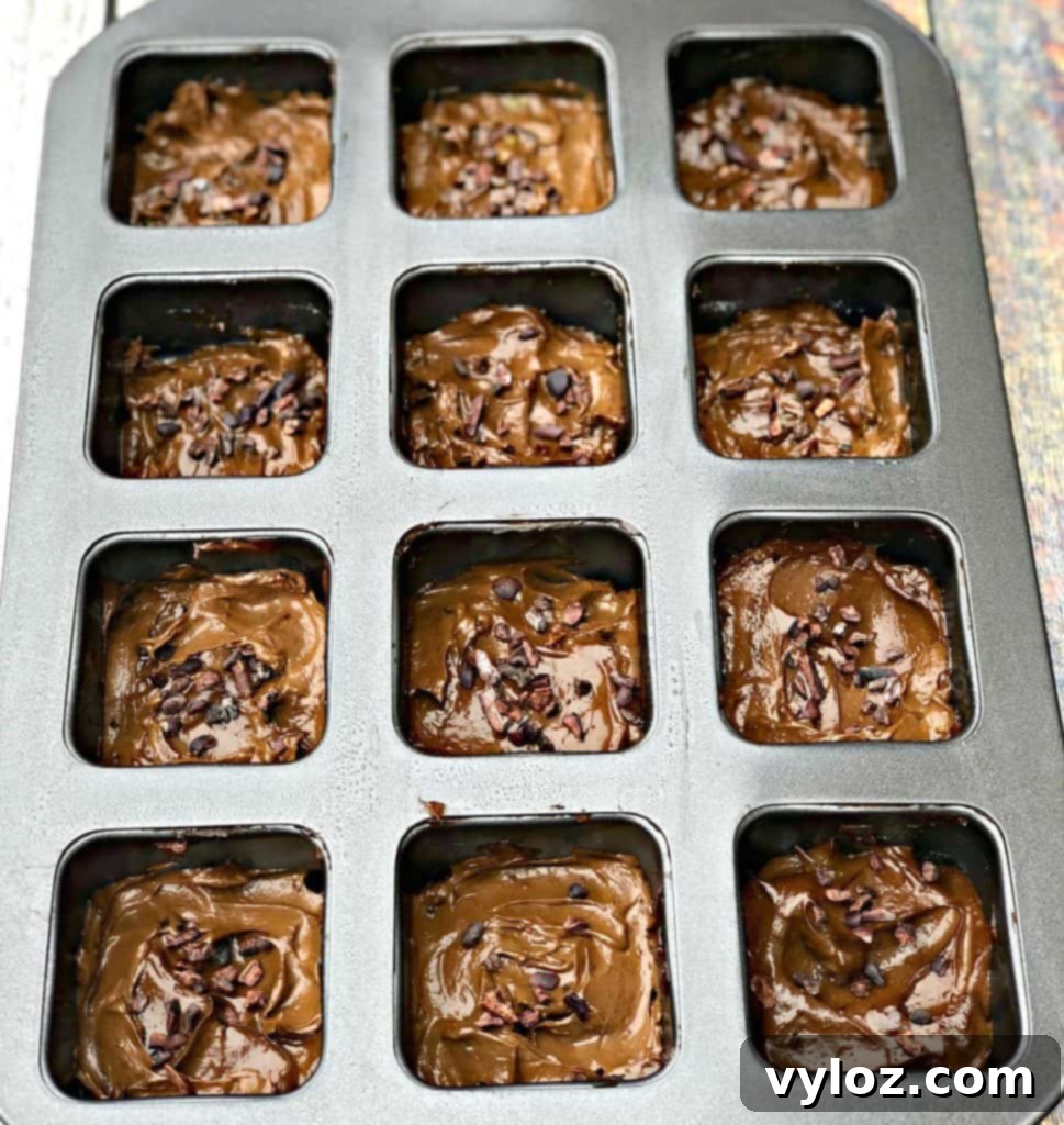 Uncooked avocado brownie batter in a square baking pan, ready for the oven