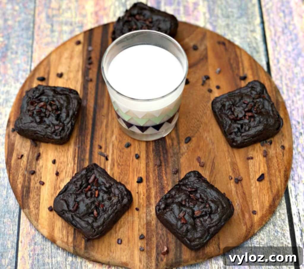 Freshly baked keto avocado brownies with a glass of milk on a brown cutting board