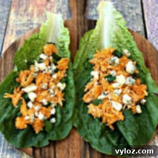 Spicy Cheesy Instant Pot Keto Buffalo Chicken Lettuce Wraps 9 buffalo chicken wraps on romaine lettuce on a cutting board with blue cheese
