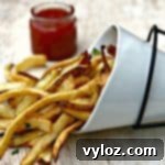 air fryer fries spread out on a brown surface with ketchup