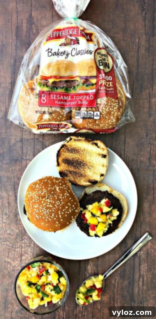 Close-up of a grilled burger with pineapple tropical salsa and fresh cilantro garnish, showcasing its vibrant appeal.