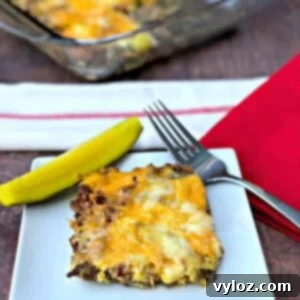 Keto Cheeseburger Bake 13 A serving of keto cheeseburger casserole with a fresh pickle slice on a white plate, ready to eat.