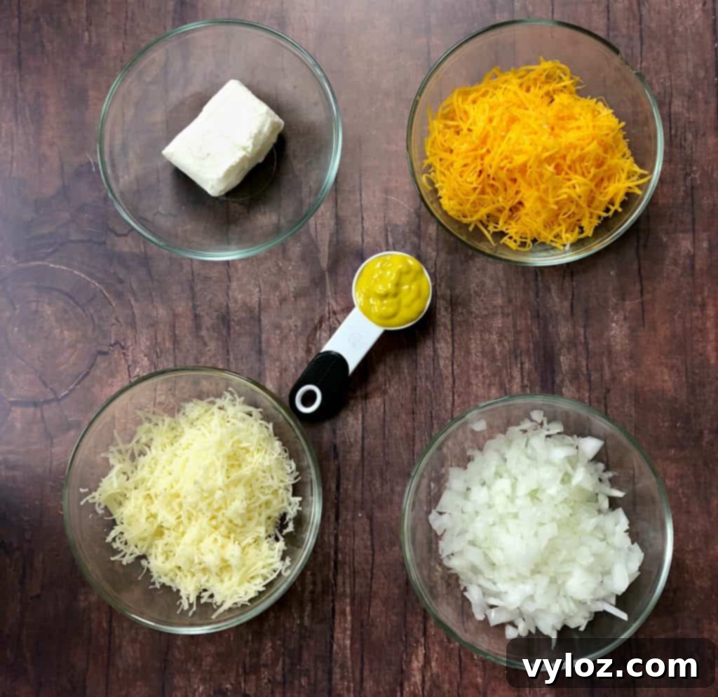 Keto Cheeseburger Bake 3 Selection of key ingredients for keto cheeseburger casserole: shredded cheese, mustard, and cream cheese in small bowls on a wooden surface.