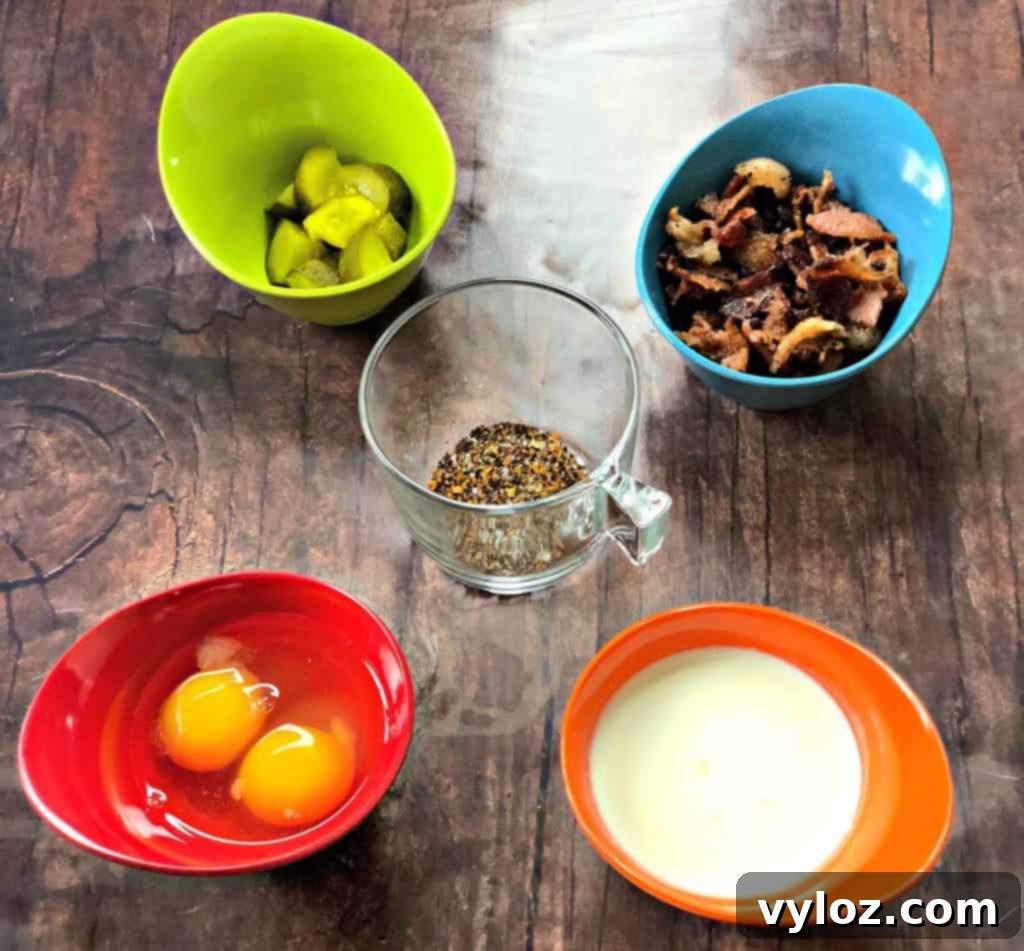 Keto Cheeseburger Bake 4 More keto cheeseburger casserole ingredients: eggs, chopped pickles, crispy bacon, and heavy cream in separate small bowls, showcasing fresh components.