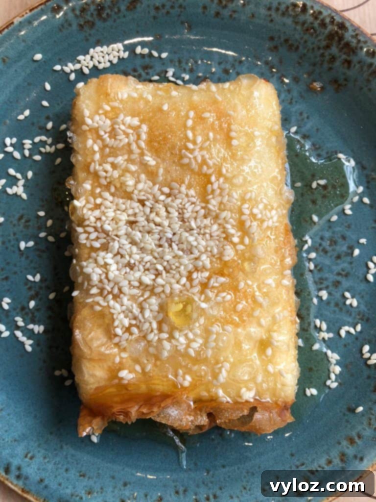 Fried feta cheese with honey and sesame seeds on a blue plate